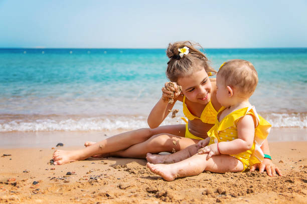 istock Smiling Girl Playing With Sister At Beach 1411402810