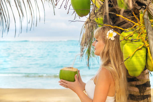 istock Woman With Flower Having Coconut Water At Beach 1411403982