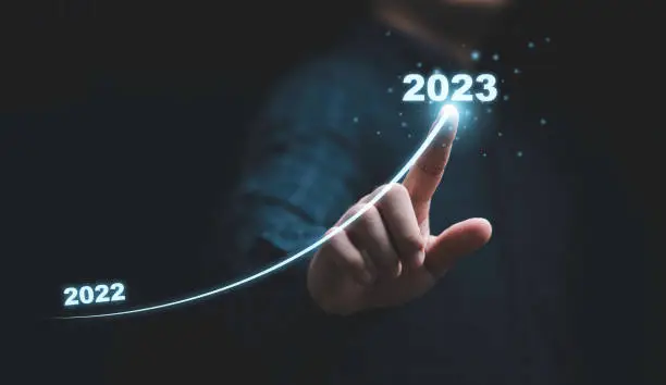 Businessman hand drawing for increasing arrow from 2022 to 2023 for preparation merry Christmas and happy new year concept.