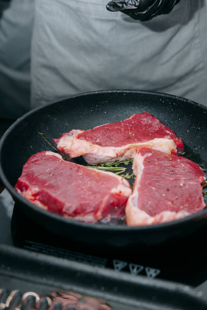 cooking steaks in a pan. cooking beef at the culinary master class. the hands of the chef in black gloves. - fine dining grilled spring onion healthy lifestyle imagens e fotografias de stock