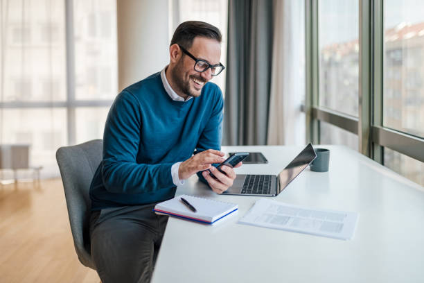 istock Happy businessman networking on smart phone while working at the desk in the office. 1411407532
