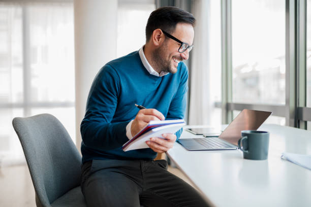 istock Smiling executive working over successful idea while looking at laptop on desk. 1411407554