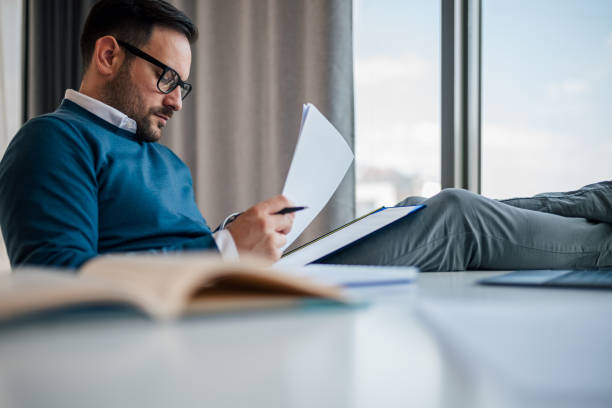 istock Focused businessman analyzing documents while sitting at the desk in the office. 1411407567