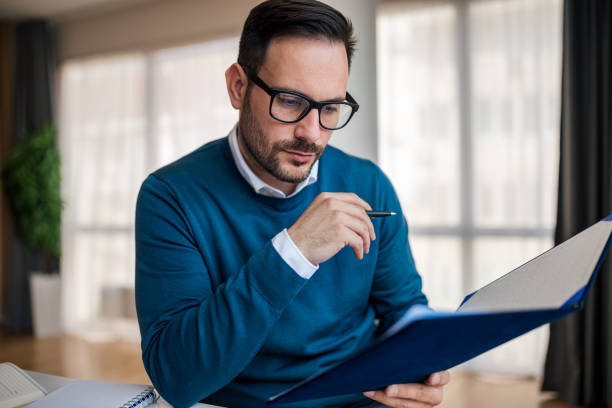 istock Serious entrepreneur analyzing documents in file while sitting at the office desk. 1411407590