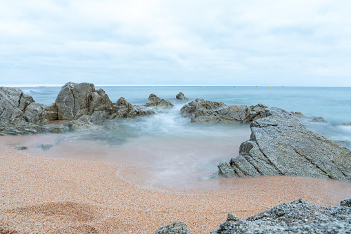 long exposure  makes misty shot of rocks in the sea with cloudy skies, at Costa Brava in Spain
