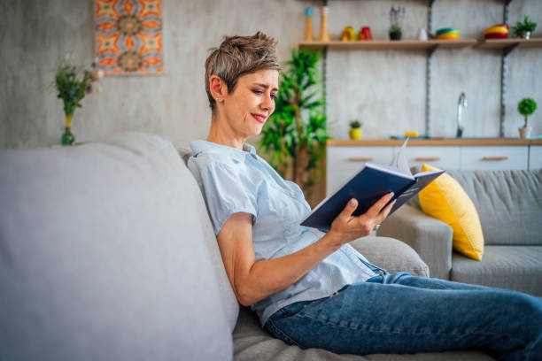 istock Woman reading a book on the sofa at home 1411409097