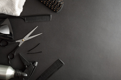 Basic conceptual hairdressing background with two scissors and comb on a black background and space to write. Top view. Horizontal composition.