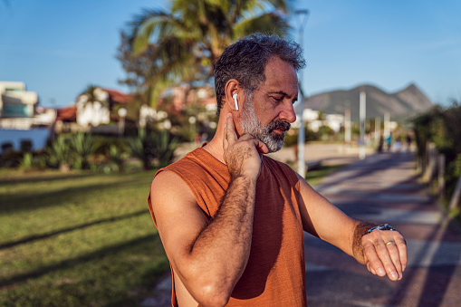 Close up of an active senior in sportswear, preparing for outdoor exercise. He is checking his pulse.