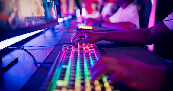 Diverse gamer group with african ethnicity players playing competitive MOBA PvP top down view computer game on a stage. Close-up on the hands