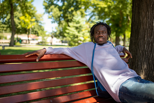 Carefree young African-American man sitting on the park bench