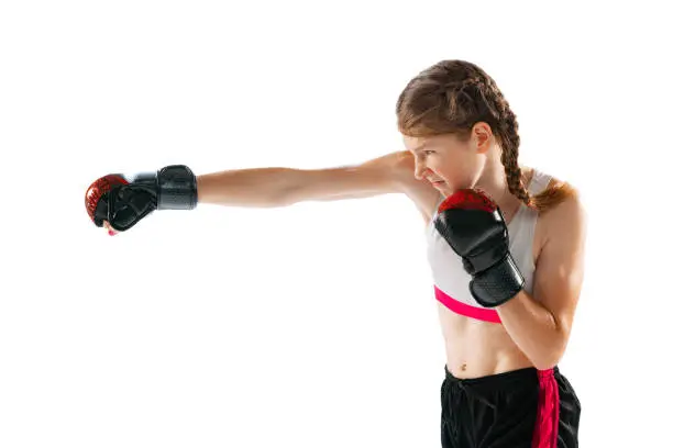 Power and energy. One sportive teen-girl, professional MMA fighter in action, motion isolated on white background. Concept of sport, competition, action, health. Copy space for ad.