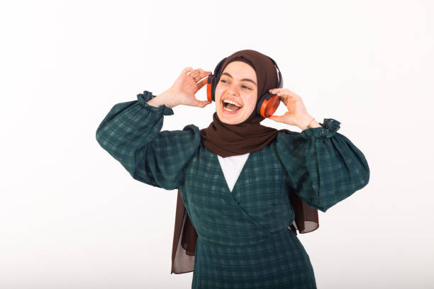 Middle east model going for portrait photos in studio. In this photo she is standing, laughing and looking away from camera while having headphones on her head.