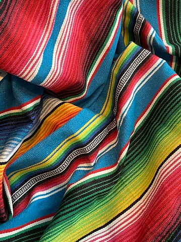 Mexican cinco de mayo poncho Mexico serape background backdrop dia de los Muertos Mexican falsa blanket rug sarape or zarape  fiesta traditional with stripes copy space backdrop - stock photo