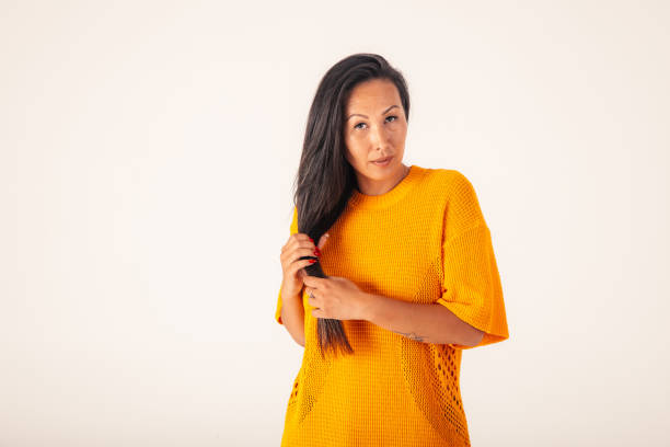 West Asian model going for portrait photos in studio. In this photo, she is standing, holding her hair in hands and looking at camera with confidence.