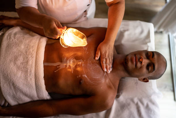 Masseuse pouring oil on customer's back