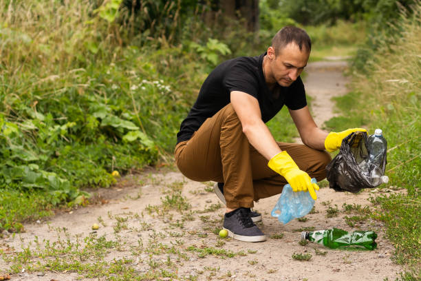 istock Young volunteer picking up plastic bottles in the park 1411430856