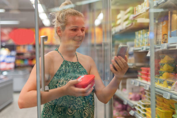 Woman using a mobile phone in a grocery store stock photo