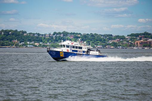 Blue and White NYPD Scuba Team Police Boat Sailing in Lower New York Harbor Towards Verrazano Bridge, NY, USA. Staten Island Shore Covered with Green Trees and Blue Sky with Clouds are in Background. Canon EOS 6D (full Frame Sensor) Camera and Canon EF 24-105mm F/4L IS lens.