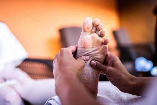 Massage therapist massaging a woman's feet at a beauty spa