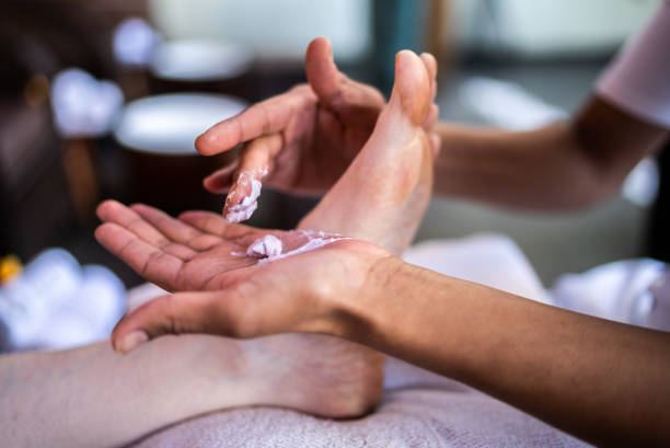 Beautician applying moisturizer on a woman's feet at a beauty spa