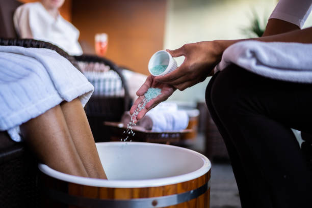 Beautician putting bath salt for a foot bath at a beauty spa