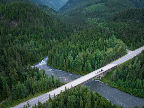Large oil truck driving along a highway. Lush forests and flowing rivers while driving along the Trans Canadian Highway in British Columbia, Canada.