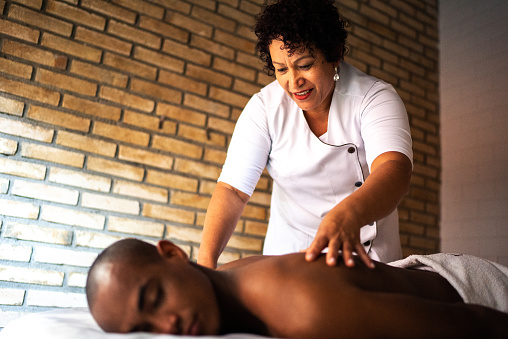 Massage therapist massaging a man's back at a beauty spa