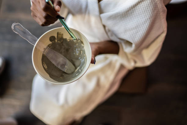 femme préparant un masque facial dans un spa - bain de boue thérapie du bien être photos et images de collection