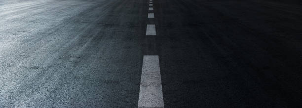 istock Asphalt road texture background, black tarmac surface with white marking stripes, Transport urban background, and Dark street texture detail. 1411436081