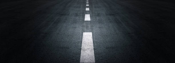 istock Asphalt road texture background, black tarmac surface with white marking stripes, Transport urban background, and Dark street texture detail. 1411436102