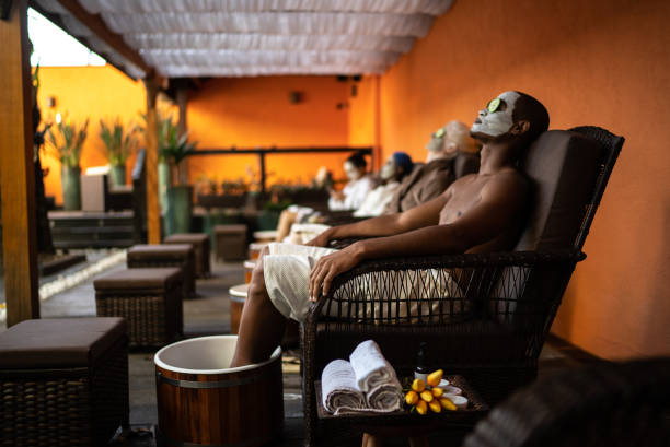 group of people in a spa doing a foot treatment with facial mask and cucumbers covering eyes - lastone therapy imagens e fotografias de stock