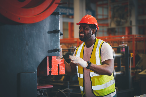 Portrait African American Black afro worker in factory, Cameroon Black man employee work in  production plant manufacture factory industry and operator line machine steel metal using helmet for safety