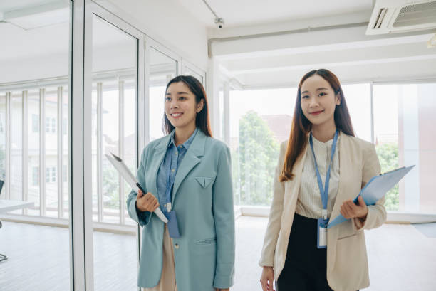 istock Asian businesswoman looking and smiling at camera while walking 1411438041