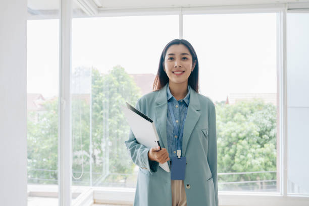 istock Asian businesswoman looking and smiling at camera while walking 1411438066