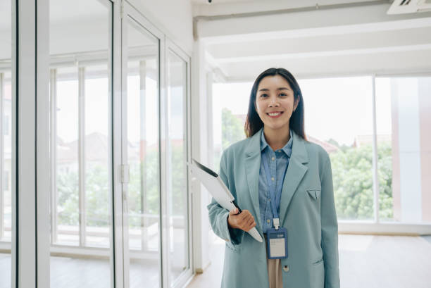 istock Asian businesswoman looking and smiling at camera while walking 1411438067