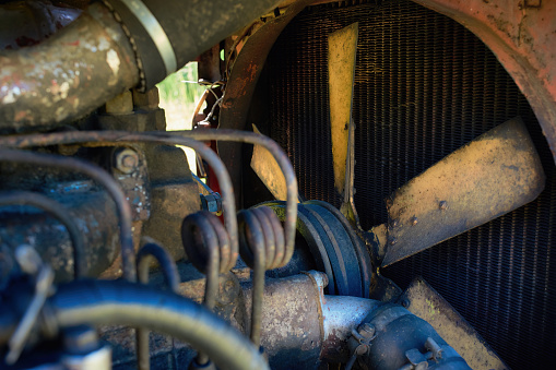 Radiator and fan of the cooling system of an old tractor. Fan drive belt. View from the engine compartment.