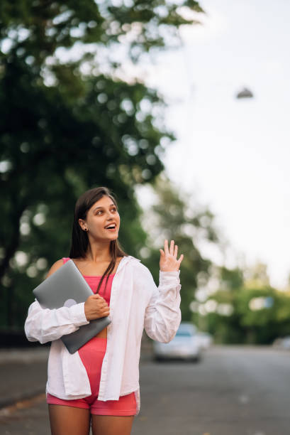 istock Young woman walking outdoors holding laptop computer 1411440755