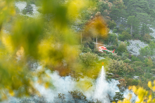 Firefithing helicopter dropping water on a  wildfire in rugged terrain