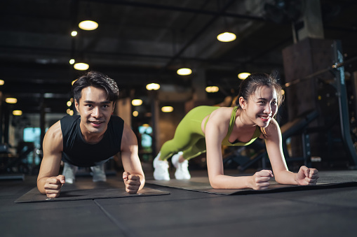 Asian couple planking together at gym. Fitness Asian couple doing plank exercise workout in fitness gym. Sport people exercising.