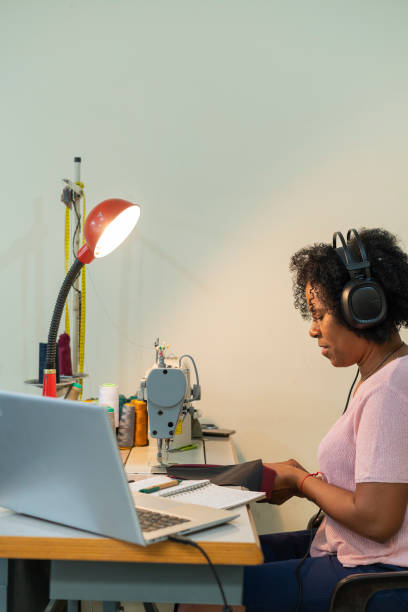istock Afro woman is in her sewing workshop taking online design classes through her laptop 1411446520
