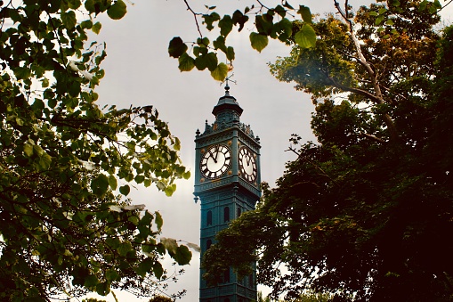 Old clock tower in Blakers Park, Brighton. Free-standing red brick and iron clock tower, 50 feet in height, and constructed in 1896. It has a square section, and rises in four stages. Its design is particularly decorative, including flower motifs, pilasters and a cupola with dolphin-shaped weather vane. The decoration is picked out in gold paint. The clock tower (and park) was donated to Brighton by Alderman Sir John Blaker, 1st baron of Brighton. His monogram is included on the clock tower.