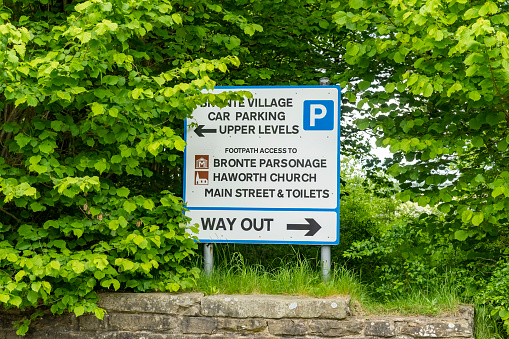 This is historic Haworth, Yorkshire, England, UK, home of the Bronte sisters.  The village has a car park near the top of the high street for coaches and cars, this is the sign for it.
