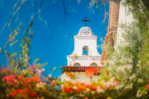 Old church in Santa Barbara county, United States of America. Blue sky in background and flowers in foreground.
