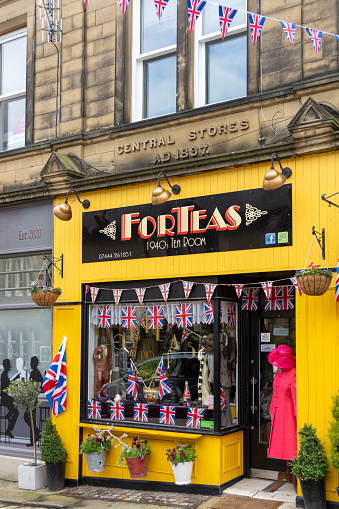 This is historic Haworth, Yorkshire, England, UK, home of the Bronte sisters.  The village is bedecked in bunting and union flags as it celebrates the Platinum Jubilee of Queen Elizabeth II.  This is the Forteas tea room which is themed on the 1940s.