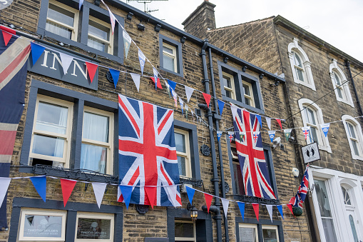 This is historic Haworth, Yorkshire, England, UK, home of the Bronte sisters.  The village is bedecked in bunting and union flags as it celebrates the Platinum Jubilee of Queen Elizabeth II.  This image is of the Fleece Inn, a pub near the top of the high street that took the celebrations especially  seriously.