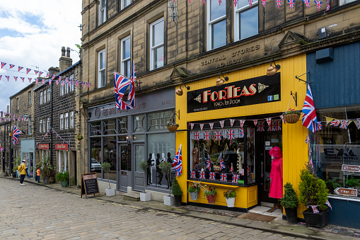 This is historic Haworth, Yorkshire, England, UK, home of the Bronte sisters.  The village is bedecked in bunting and union flags as it celebrates the Platinum Jubilee of Queen Elizabeth II.  This is the Forteas tea room which is themed on the 1940s.