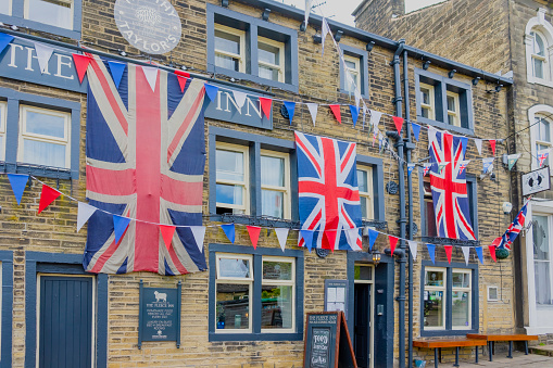 This is historic Haworth, Yorkshire, England, UK, home of the Bronte sisters.  The village is bedecked in bunting and union flags as it celebrates the Platinum Jubilee of Queen Elizabeth II.  This image is of the Fleece Inn, a pub near the top of the high street that took the celebrations especially  seriously.