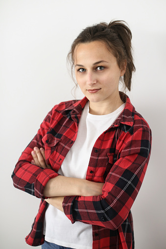 Portrait of a young woman with crossed arms on white background. About 20 years old, Caucasian female.