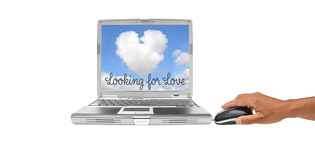 Hand on mouse next to laptop with Heart Shaped Cloud and Looking for Love on the screen
