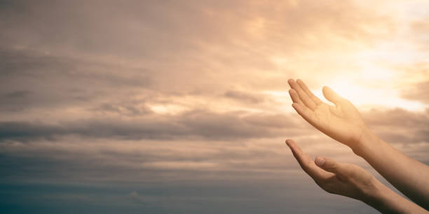 istock Woman hands praying for blessing from god with sunlight on sunset background. 1411455351